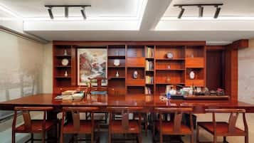 A dining area with a long wooden table and chairs, surrounded by wooden bookshelves filled with books and decorative items.