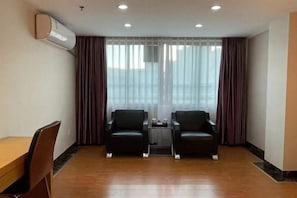 A room with two black leather chairs, a small table, and a wooden desk.