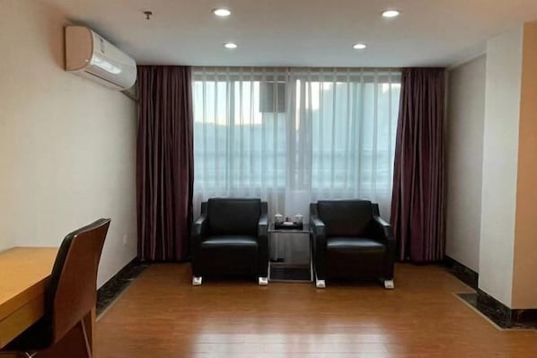 A room with two black leather chairs, a small table, a wooden desk, and a large window with curtains. - Foshan Convergence Fashion Hotel (Foshan)