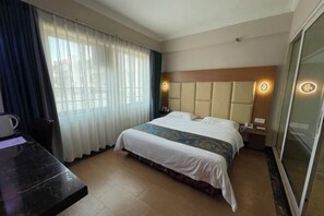 A hotel room with a bed, a desk, and a large window with curtains. - Foshan Convergence Fashion Hotel (Foshan)