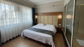 Une chambre d’hôtel avec un grand lit, une tête de lit en bois, une table de chevet avec une lampe et un placard à portes coulissantes en verre.