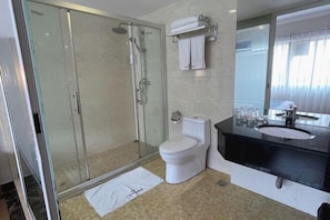 A modern bathroom with a glass shower enclosure, a white toilet, a black sink, and a large mirror. - Foshan Convergence Fashion Hotel (Foshan)