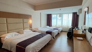 Une chambre d’hôtel avec trois lits, un bureau, une chaise et un téléviseur.