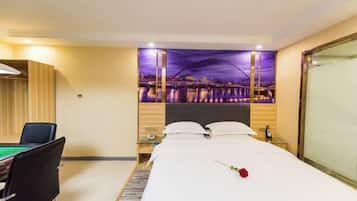A hotel room with a bed, a desk with a pool table, and a cityscape view.