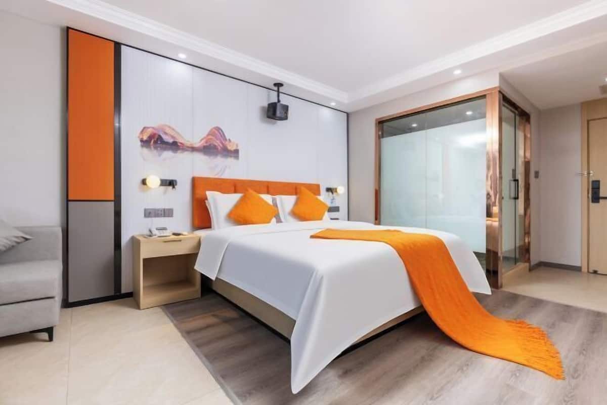 A modern hotel room with a bed, bedside table, and a large window.