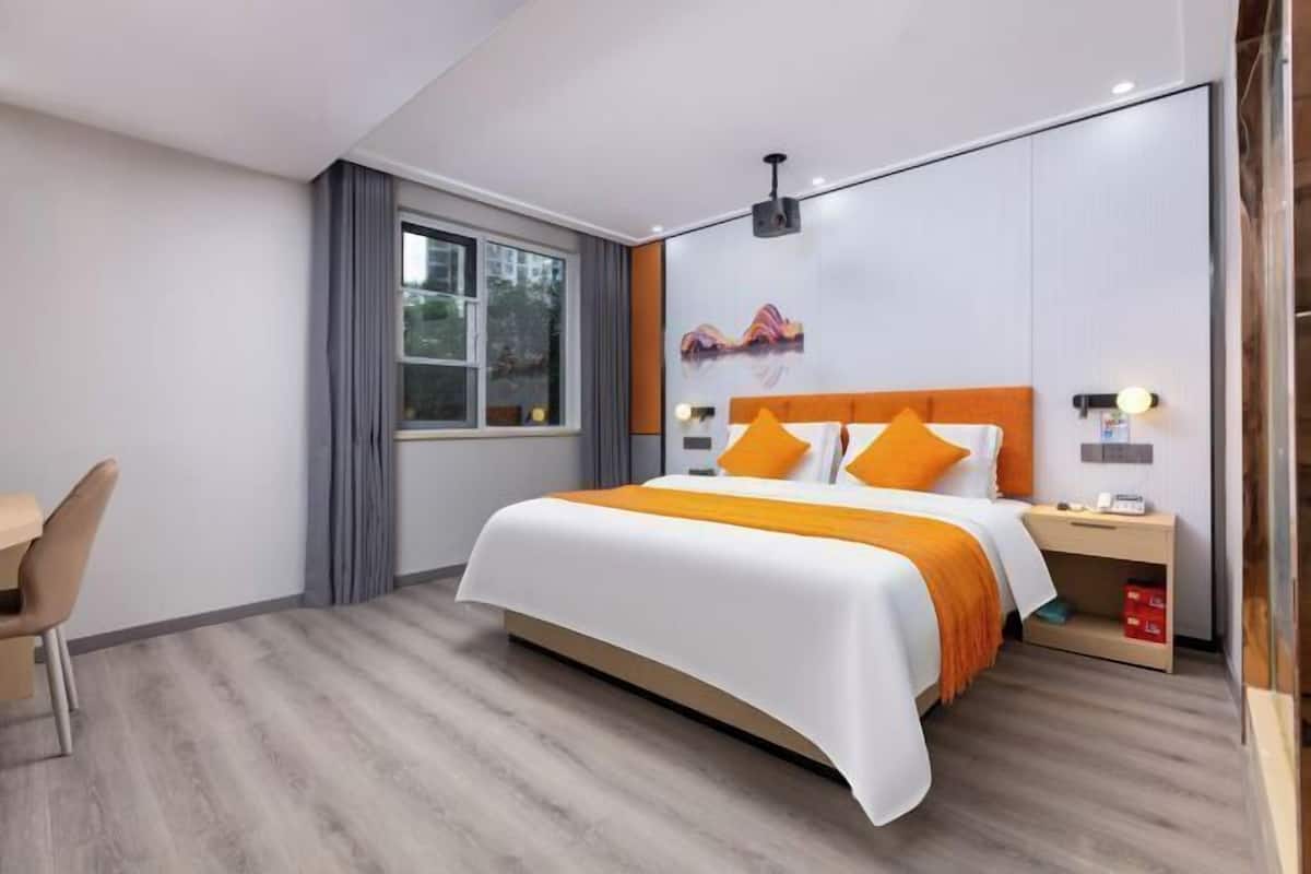 A modern hotel room with a large bed, a desk, and a window.