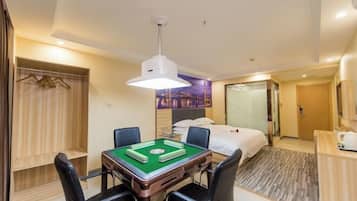 A hotel room with a green pool table, a bed, a desk with a lamp, and a wardrobe.