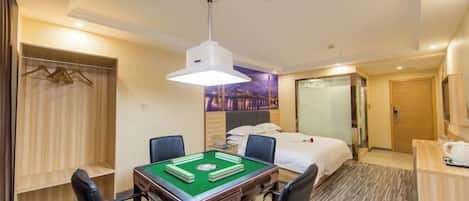Una habitación de hotel con una mesa de billar verde, una cama, un escritorio con una lámpara y un armario.