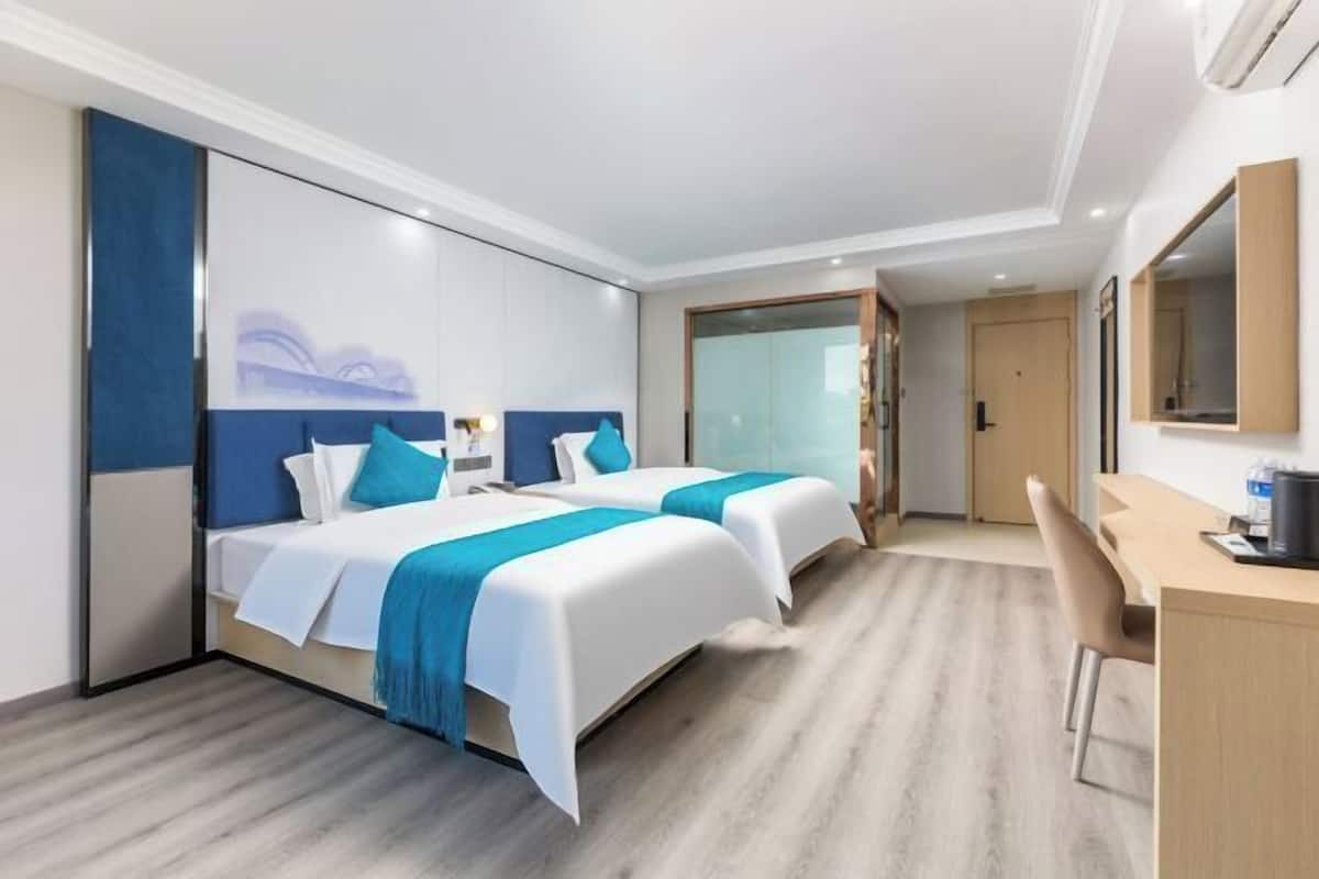 A hotel room with two beds, a desk, and a chair.