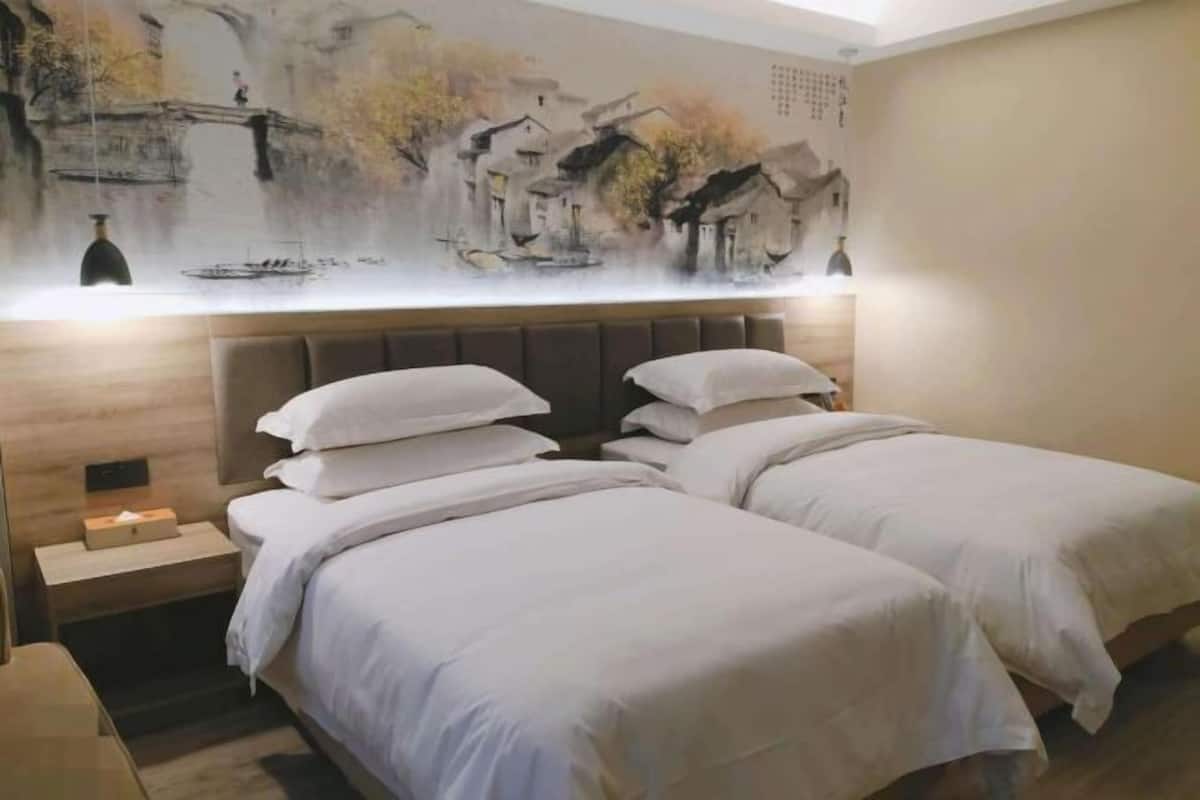 A hotel room with two beds, a nightstand, and a wall mural.