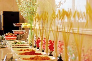 A buffet table with various dishes and floral centerpieces.