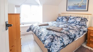 Ein Schlafzimmer mit einem Bett, einem Fenster, einem Gemälde und einer Holztür.