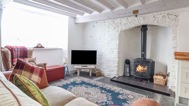 Ein gemütliches Wohnzimmer mit Kamin, Flachbildfernseher und bequemen Sitzgelegenheiten.