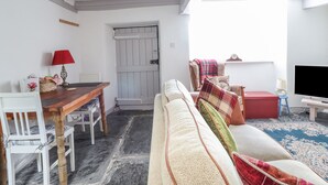 Ein gemütliches Wohnzimmer mit einem Holzespeisetisch, einem weißen Sofa und einem roten Sessel.