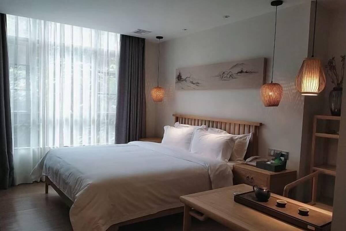 Een hotelkamer met een bed, nachtkastje, lamp en kunst aan de muur.