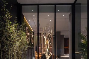 Un intérieur moderne avec une cloison en verre, des plantes d’intérieur et un escalier menant à un niveau supérieur.
