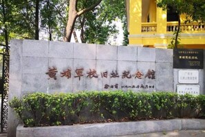 A stone monument with inscriptions, surrounded by a low hedge and trees. - Helen Jiangnanfeng Art Hotel (Guangzhou University Town Store) (Guangzhou)