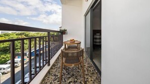 Un balcón con mesa y sillas, barandilla y vista de la calle.