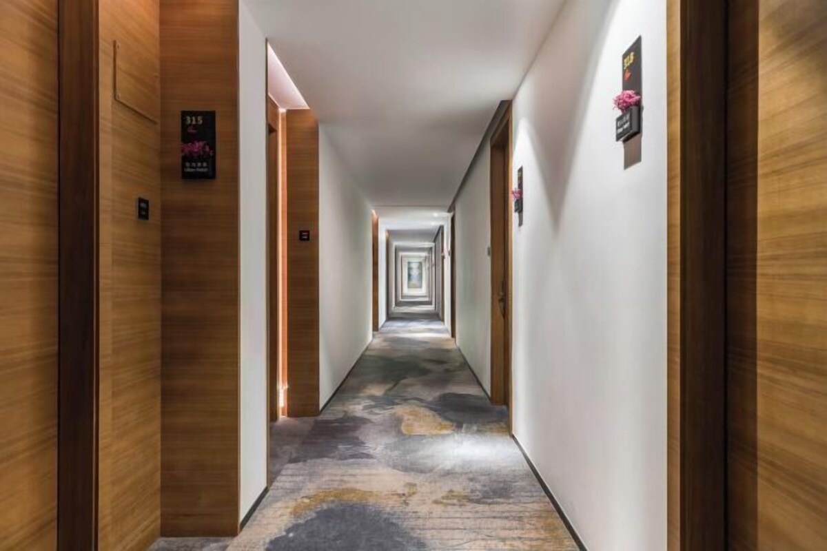 Un largo y estrecho pasillo de hotel con paneles de madera en las paredes y una alfombra estampada.