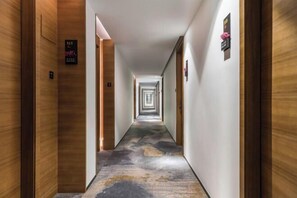 Un largo y estrecho pasillo de hotel con paneles de madera en las paredes y una alfombra estampada.