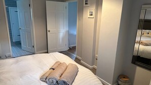 Una habitación de hotel con una cama, un baño y un pasillo.