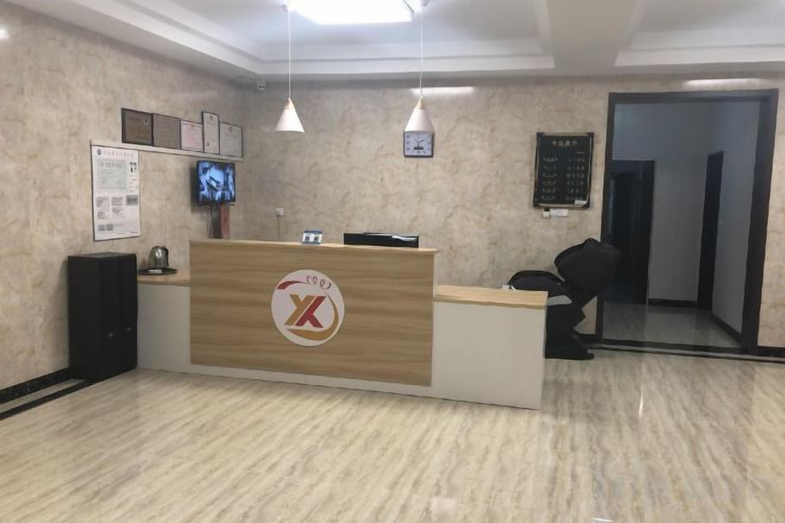 Una mesa de recepción con un logotipo, un televisor y un reloj en la pared.