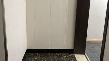 Un pasillo estrecho con piso de mármol, una obra de arte enmarcada en la pared y una puerta al final.