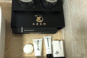 A black box with a logo and Chinese characters, containing a toothbrush and three tubes of cream.