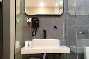 A bathroom with a white sink, a mirror above it, and a hand dryer on the wall.