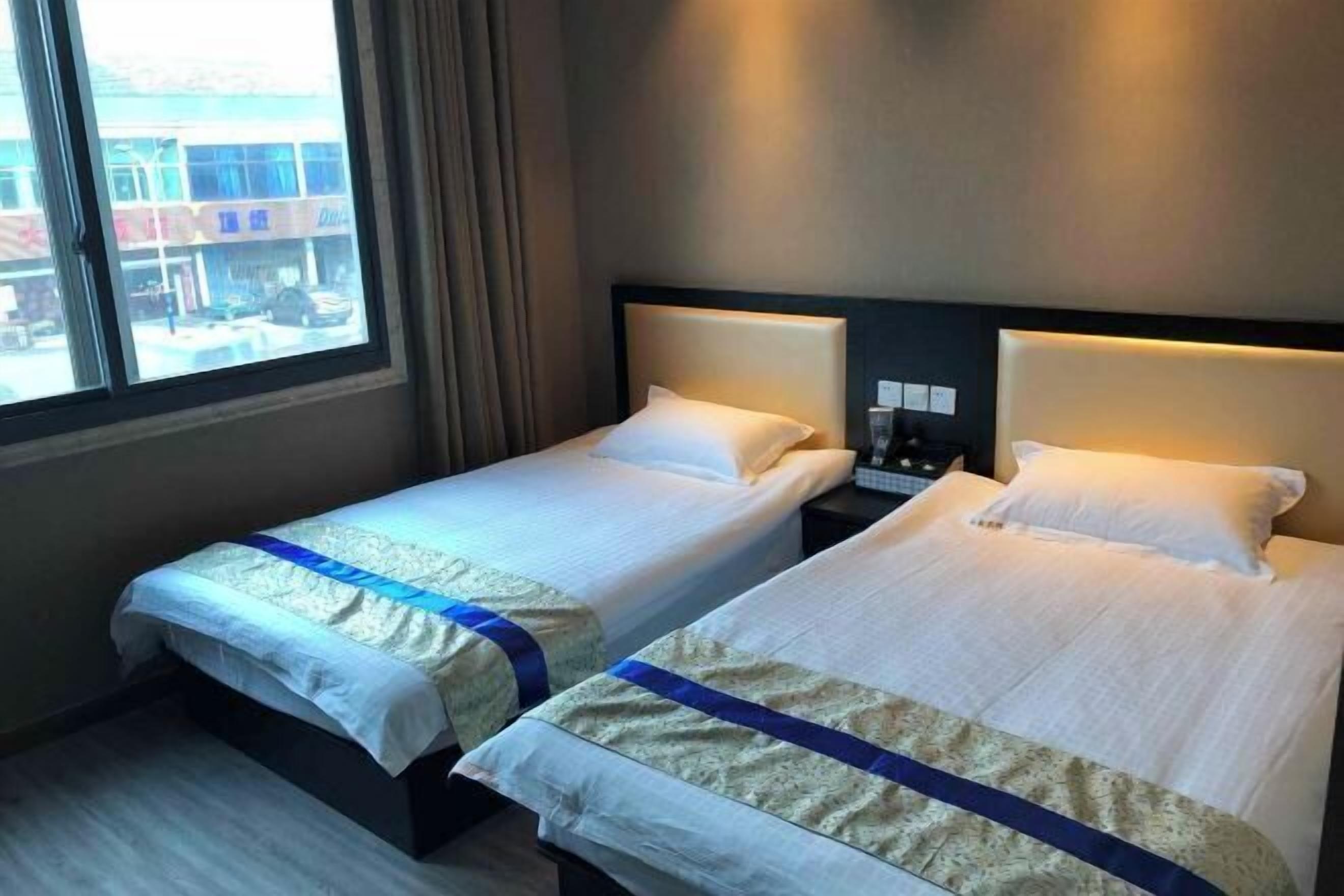 A hotel room with two beds, each with a headboard and a bedside table.