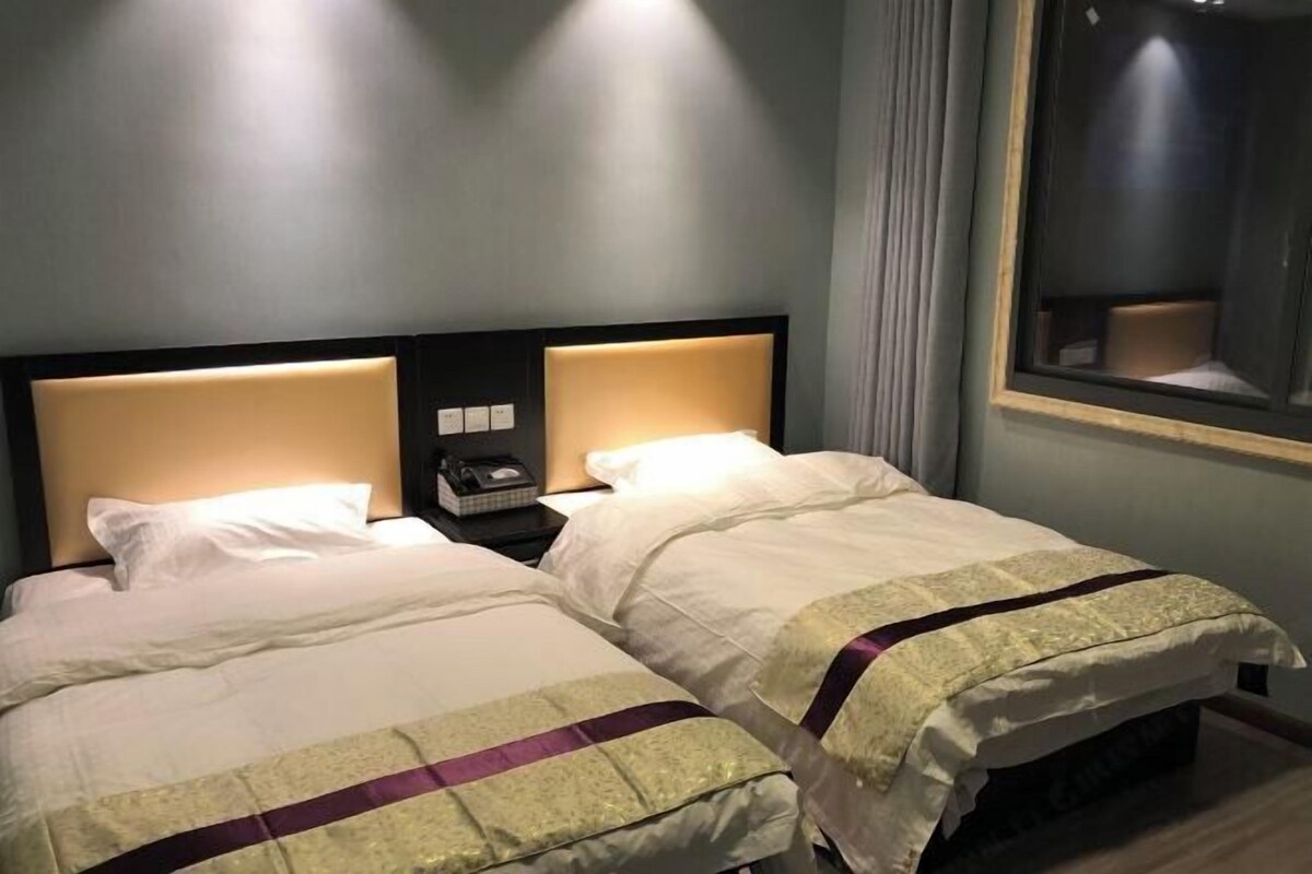 A hotel room with two beds, each with a headboard and bedside tables.