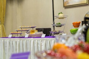 A buffet table with various food items and a tiered serving stand.