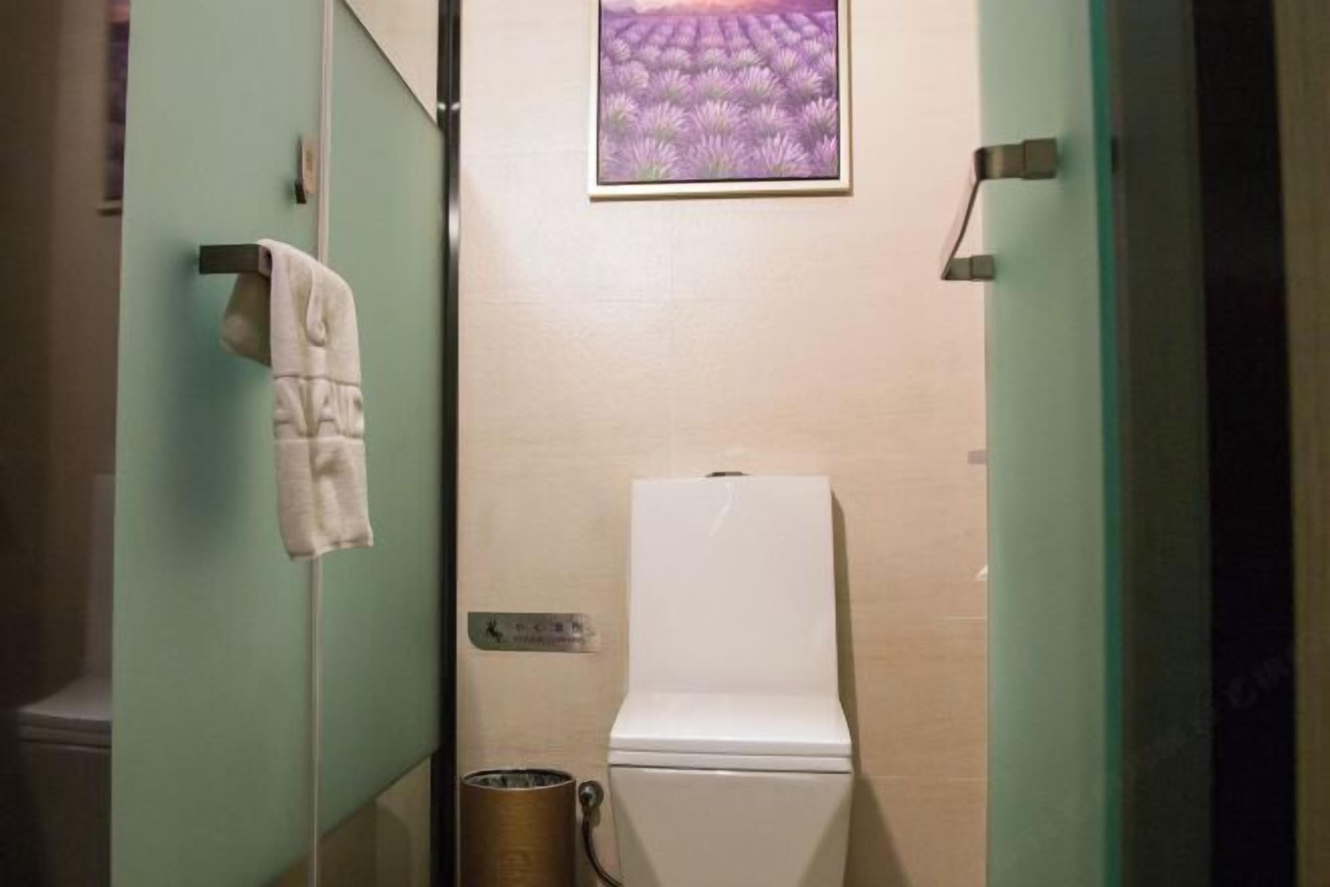 A bathroom with a toilet, a towel rack, and a trash can.
