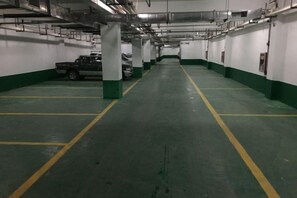 A multi-level parking garage with green and white walls, yellow parking lines, and a truck parked in the distance. - Lavande Hotel (Longnan Changjiang Avenue) (Longnan)