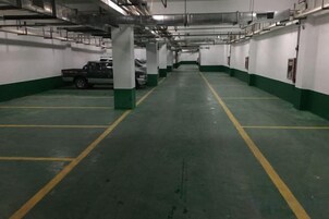 Un aparcamiento de varios niveles con paredes verde y blanco, líneas de aparcamiento amarillas y un camión estacionado a lo lejos.