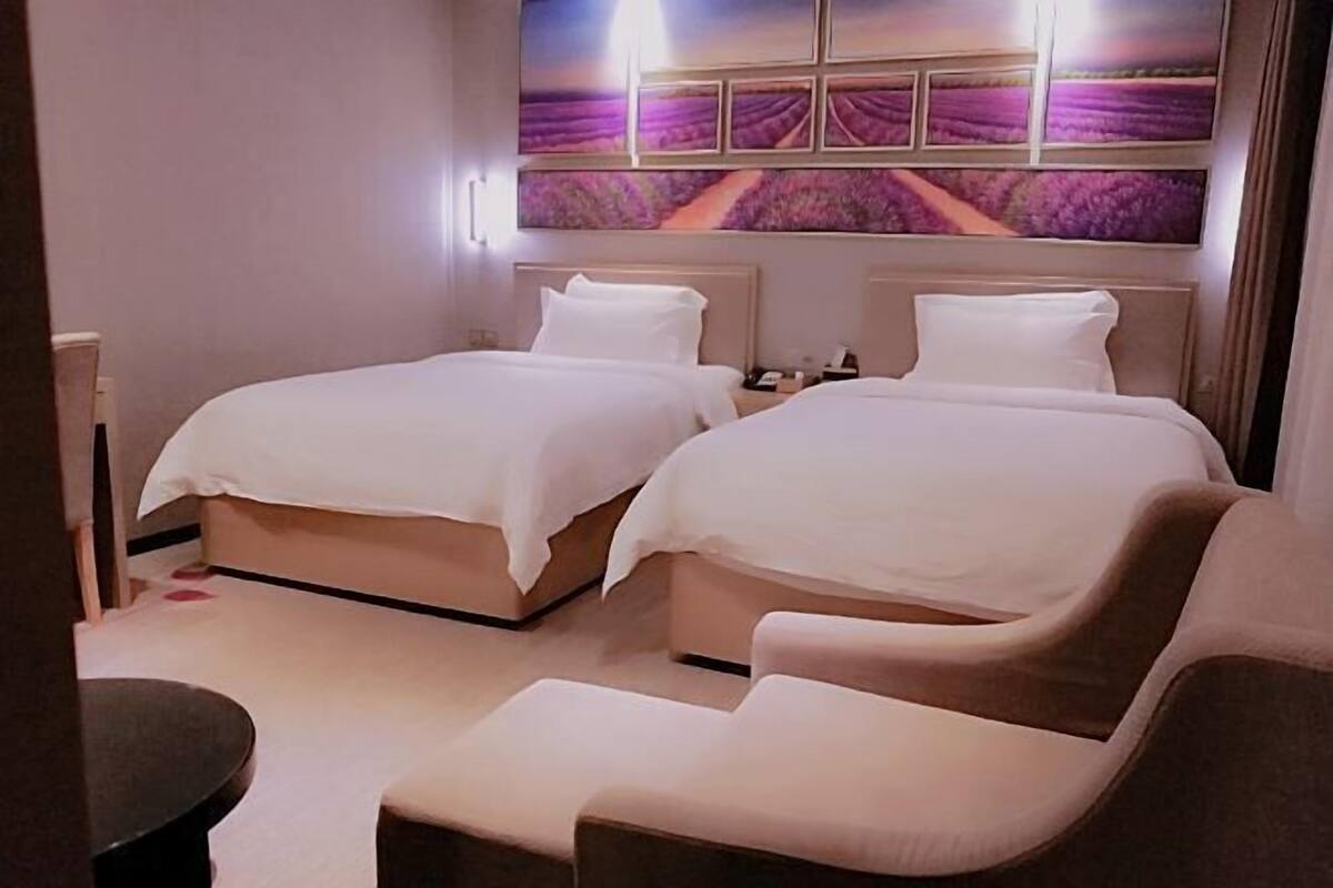 Hotellihuone, jossa on kaksi sänkyä, pieni pöytä ja tuoli.