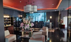 A modern lobby with a reception desk, seating area, and a bar.