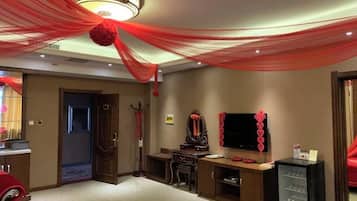 A room with a desk, chair, television, and a decorative red hanging from the ceiling.