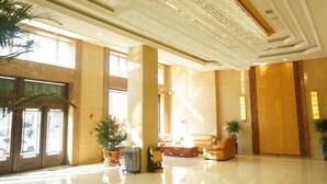 A spacious lobby with a high ceiling, large windows, and a seating area with sofas. - East Guesthouse (Muling)