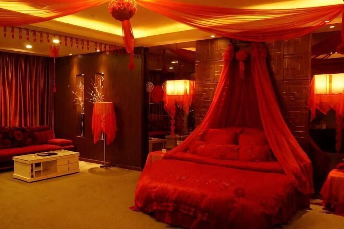 Una habitación con una cama con dosel rojo, un sofá y una pequeña mesa.