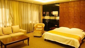 A hotel room with a bed, a sofa, a chair, a coffee table, and a lamp. - East Guesthouse (Muling)