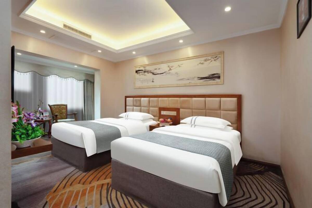 Une chambre d’hôtel avec deux lits, une grande œuvre d’art au mur et un design moderne au plafond.