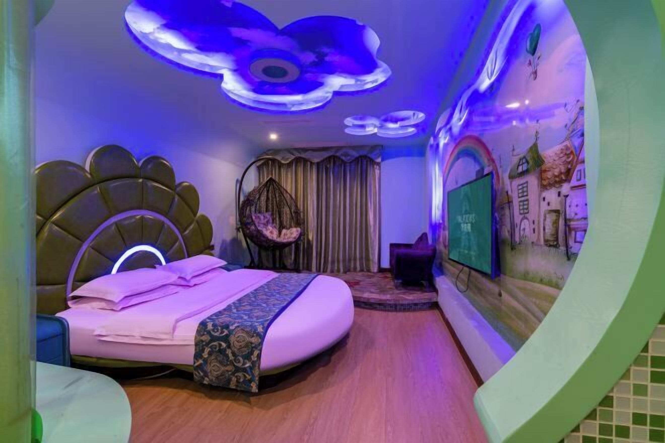 A bedroom with a modern design, featuring a bed with a unique headboard, a hanging chair, and a wall with a mural.