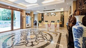 Eine Hotelhalle mit Marmorboden, einer Rezeption und einer großen Ziervase.
