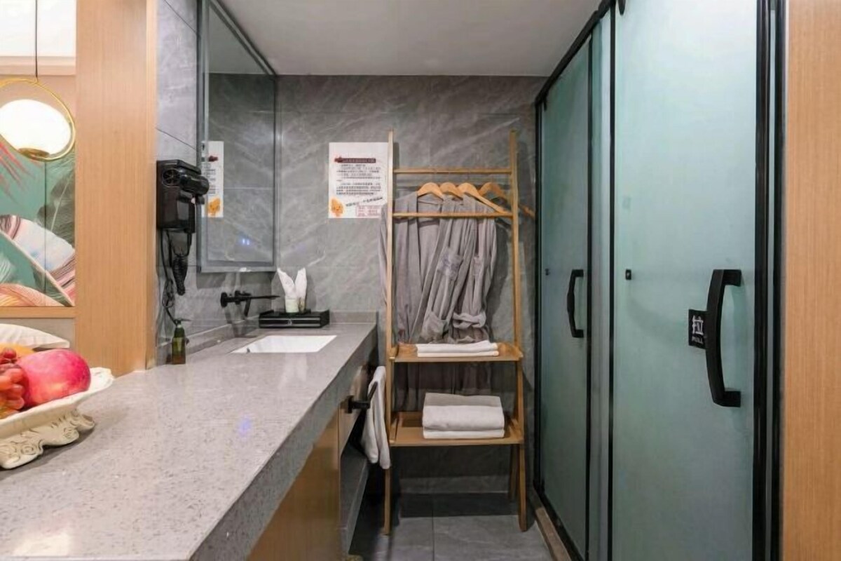 Uma casa de banho de hotel compacta, com lavatório, porta-toalhas e zona de duche.