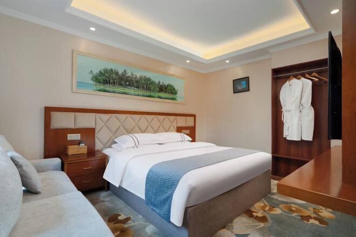 Une chambre d’hôtel avec un lit, une table de chevet, une armoire et un tableau au mur.