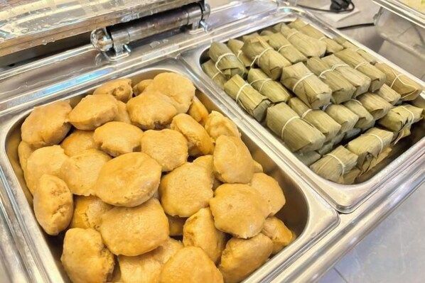Un bufé con dos tipos de comida: una en un recipiente metálico y otra en una bandeja.