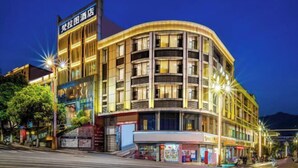 Un hotel de varios pisos con fachada curva, señalización iluminada y espacio comercial en la planta baja.