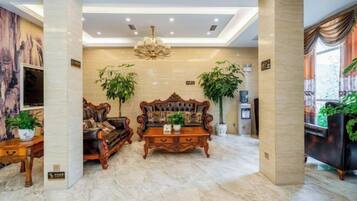 A spacious living room with a large sofa, a coffee table, and two potted plants.