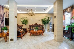 A spacious living room with a large sofa, a coffee table, and two potted plants. - Valatoms Fanlatu Hotel (Shuifu Municipal Government) (Shuifu)